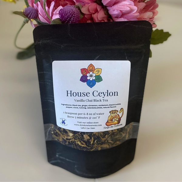 Black tea package with 'House Ceylon' label and flowers in the background