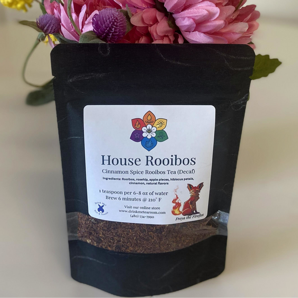 Black tea packaging with a colorful label featuring 'House Rooibos' on a light background with flowers.